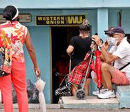 Varias personas esperan fuera de una oficina de Western Union, este jueves en La Habana, (Cuba). (EFE)