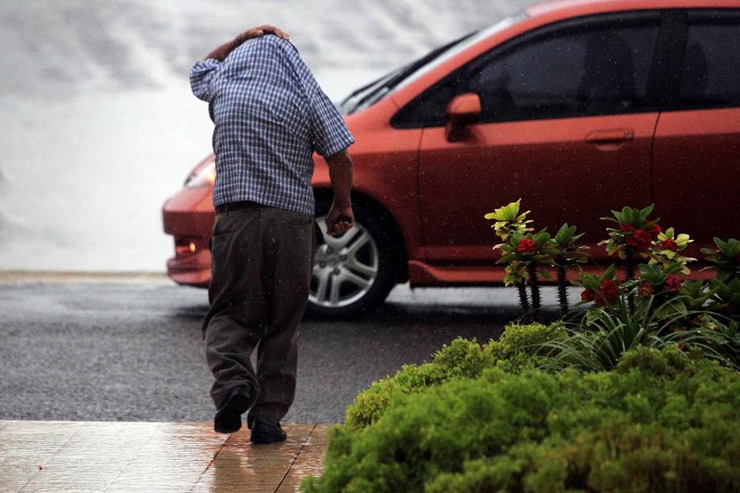 Un hombre se cubre con su camisa para evitar mojarse con la lluvia. (GFR Media)