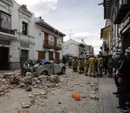 Los equipos de rescate se paran junto a un automóvil aplastado por los escombros a causa de un terremoto, en Cuenca, Ecuador, el sábado 18 de marzo de 2023. (Foto AP/Xavier Caivinagua)