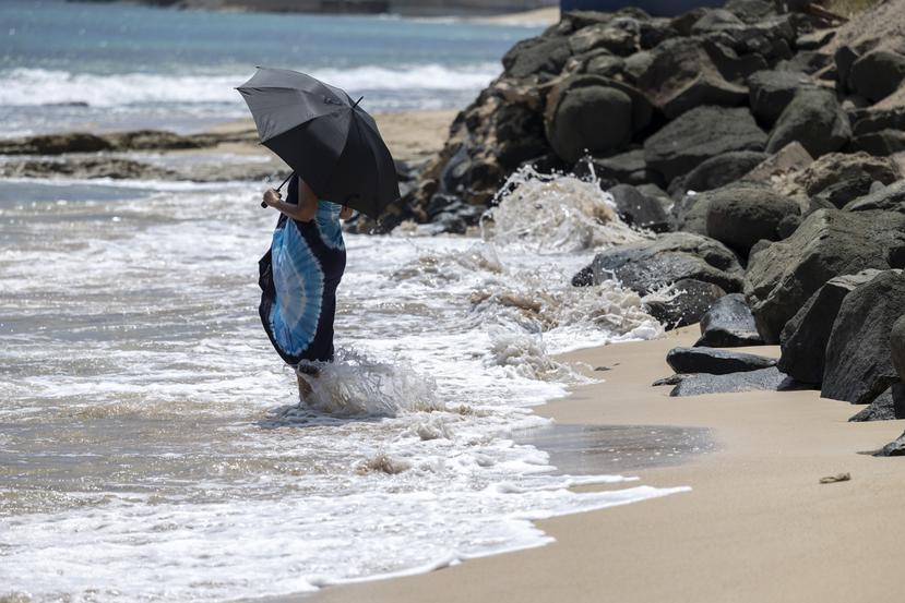 Una mujer se refresca los pies en la playa bajo una sombrilla, durante un aviso de calor extremo, el 9 de junio de 2023.