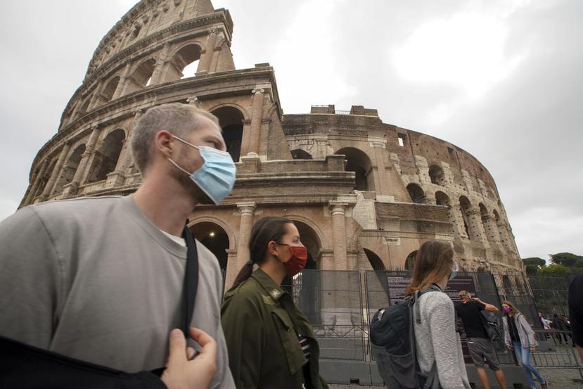 Las personas utilizan una mascarilla para prevenir contagios mientras caminan por al frente del Coliseo en Roma, Italia.