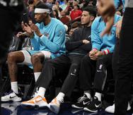 Devin Booker, base de Suns de Phoenix, de negro, está sentado en la banca, al lado de Torrey Craig en la primera mitad del juego de baloncesto de la NBA en contra de los Nuggets de Denver, el domingo 25 de diciembre de 2022, en Denver.