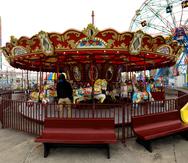 El operador de carrusel espera a la gente en la reapertura del Luna Amusement Park en Coney Island, Nueva York, Nueva York. Al fondo, la famosa noria del parque de atracciones, uno de los símbolos de Nueva York.