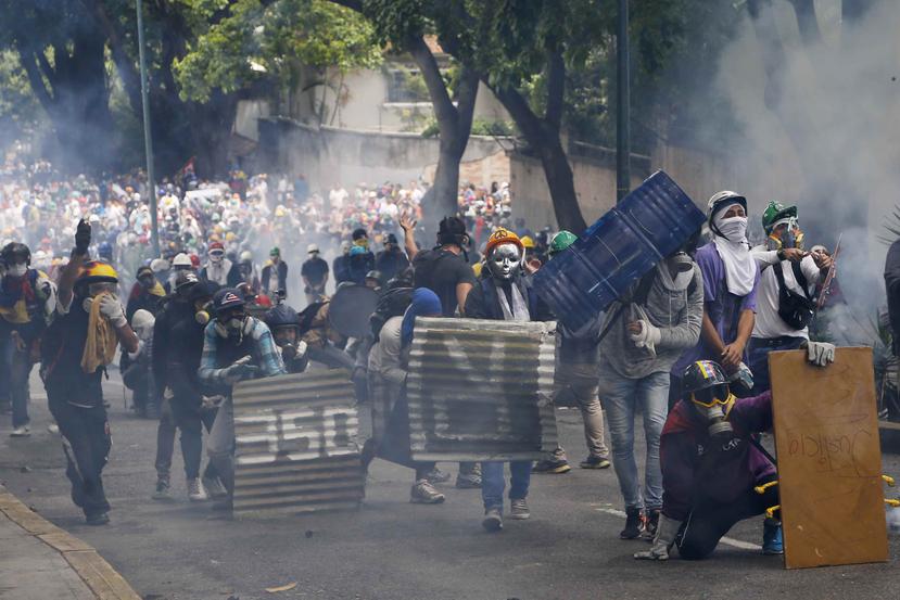 Centenares de opositores bloquearon algunas vías del este y oeste de Caracas con barricadas de basura, árboles, escombros, metales retorcidos y hasta banderas venezolanas de varios metros de largo que fueron colgadas entre los postes de luz. (AP)