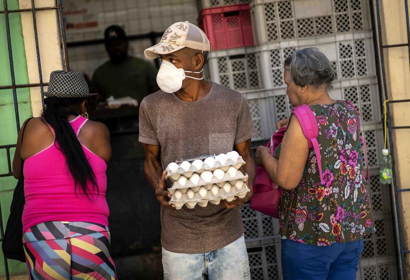 Un hombre con una mascarilla sale de una estación del gobierno con una ración de huevos en La Habana. (AP)