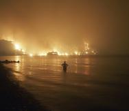 Un hombre observa un incendio cerca de la playa de Kochyli cerca del pueblo de Limni, en la isla de Evia, a unos 160 kilómetros (100 millas) al norte de Atenas, la noche del viernes 6 de agosto de 2021.