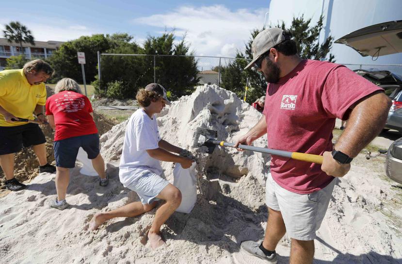 Walker Townsend, de Isle of Palms, en Carolina del Sur, llena un saco de arena que sostiene Dalton Trout, en un estacionamiento municipal donde se reparte arena de forma gratuita dentro de los preparativos para la llegada del huracán Florence a la región.