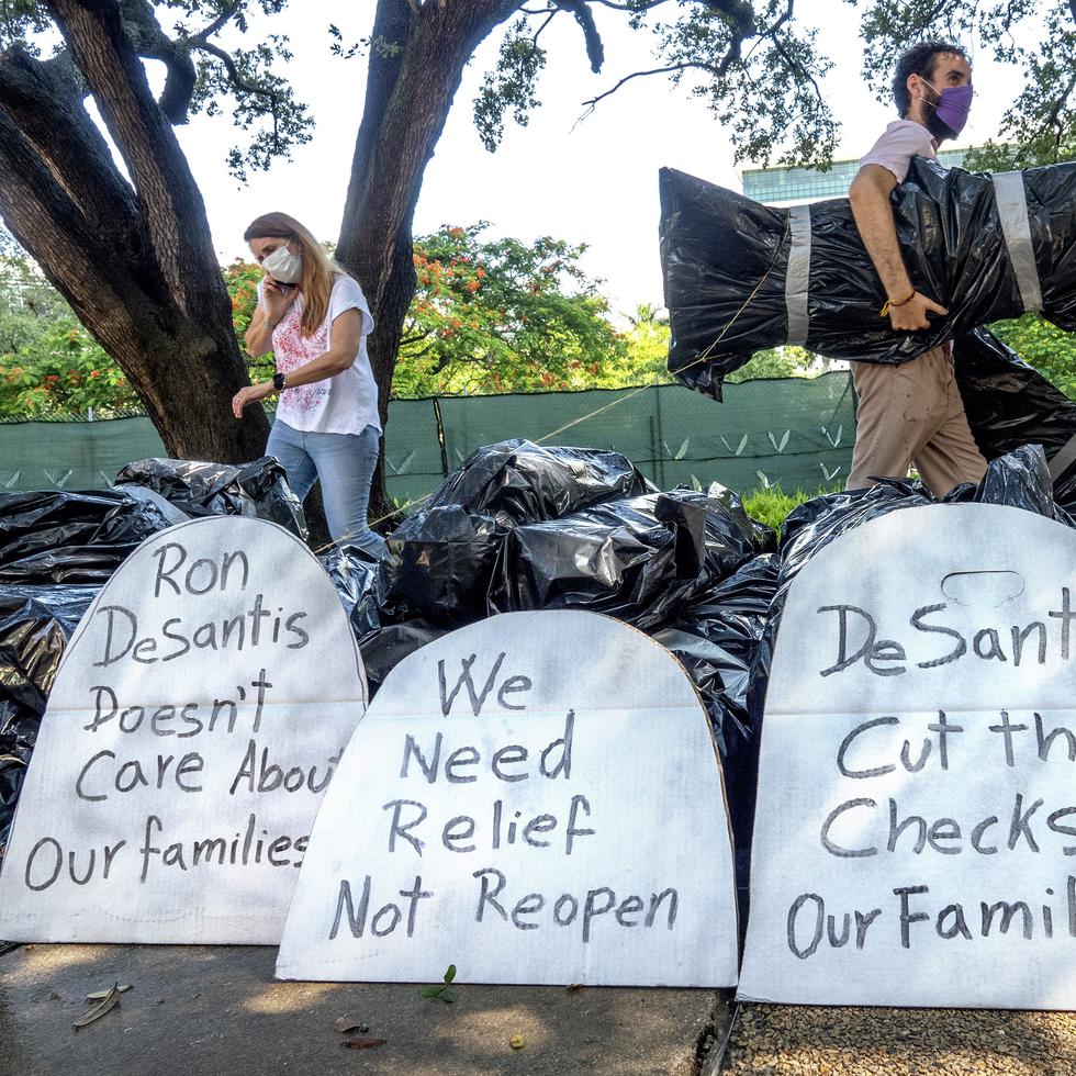 Activistas protestan utilizando bolsas de basura que aluden a los muertos por COVID-19 en momentos en que el gobernador de Florida, Ron DeSantis, insiste en la reapertura económica.