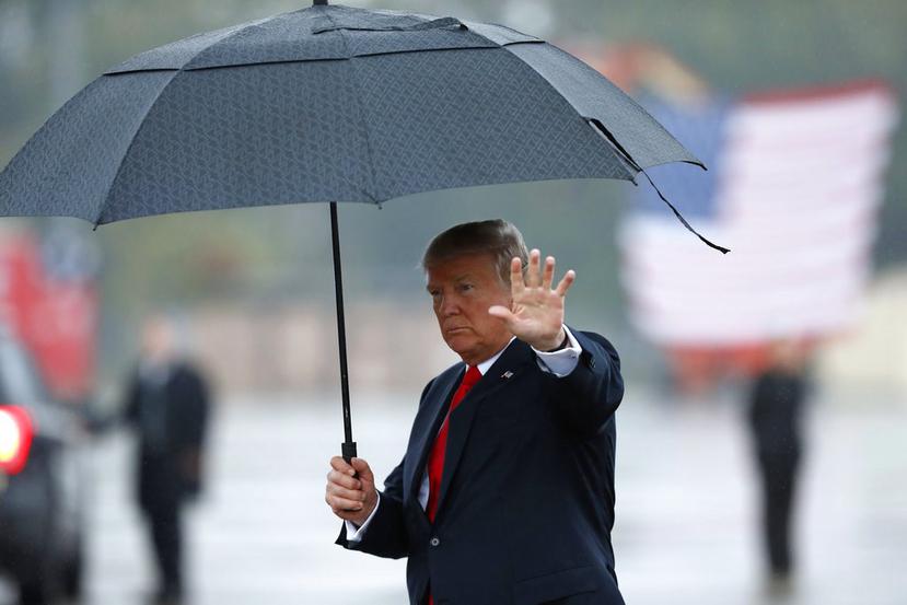President Donald Trump waves as he carries an umbrella walking on the tarmac to his limousine at Harrisburg International Airport, Wednesday Oct. 11, 2017, in Middletown, Pa. (AP Photo/Alex Brandon)