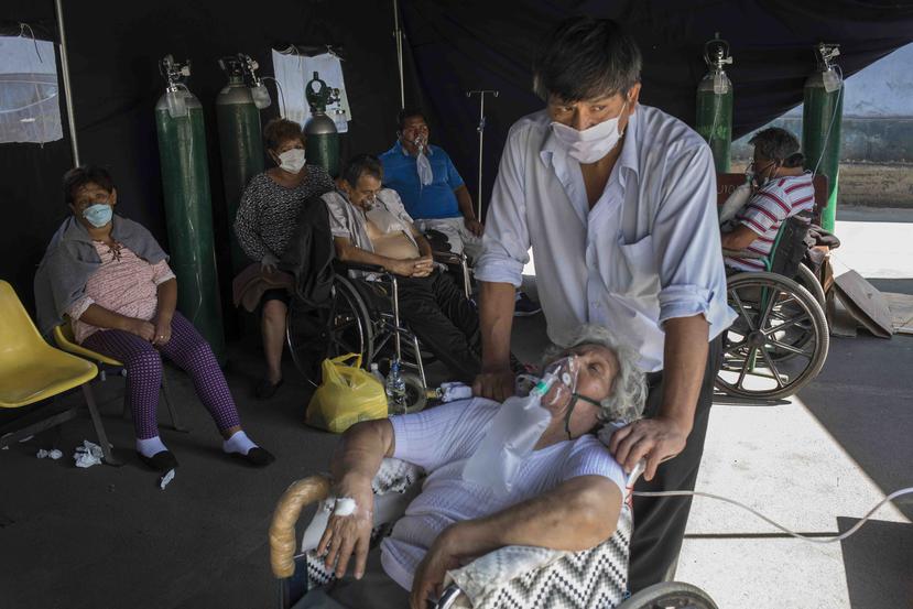 Emma Salvador, de 84 años y con una mascarilla de oxígeno para ayudarle a respirar, es vigilada por su hijo José González en una tienda improvisada que se instaló en el Hospital Dos de Mayo para tratar a las personas infectadas con el nuevo coronavirus, e