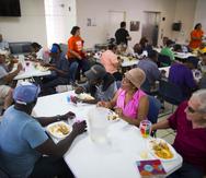 Personas que hacen labor voluntaria sirven el almuerzo de los participantes.
