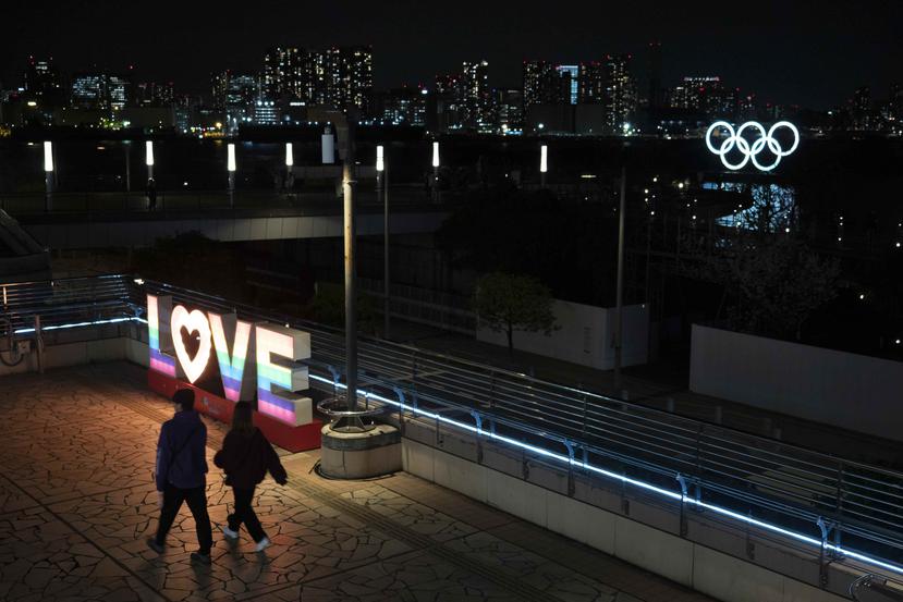 Con los anillos olímpicos en la distancia, una pareja camina en el distrito de Odaiba en Tokio. (AP)