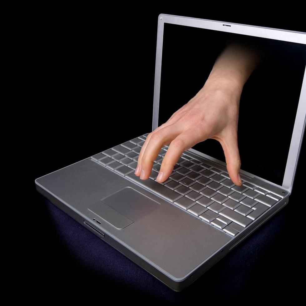 A hacker concept image of a hand coming through the computer. computer virus