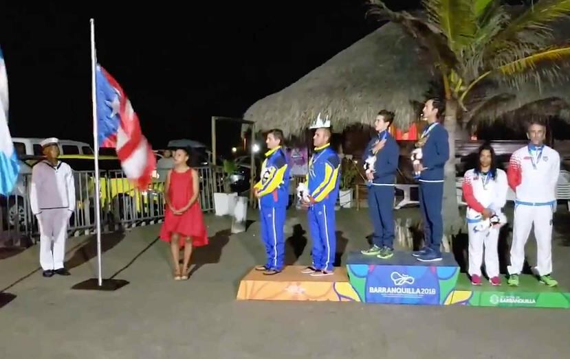 Momento en que Quique Figueroa y Franchesca Valdés rehusan mirar las banderas a manera de protesta por la decisión que les costó la medalla de oro en Barranquilla. (Archivo / GFR Media)