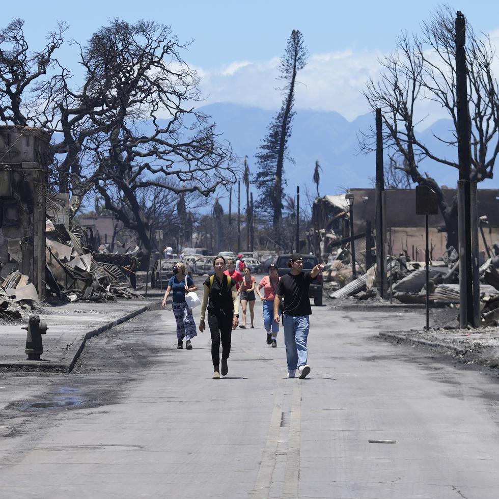 Unas personas caminan por una calle ante los daños causados por un incendio forestal, el viernes 11 de agosto de 2023, en Lahaina, Hawai.