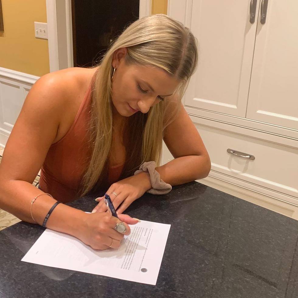 Laura Stockton, hija del miembro del Salón de la Fama John Stockton, firmando su contrato que le permitirá jugar en Puerto Rico con las Montañeras de Morovis.