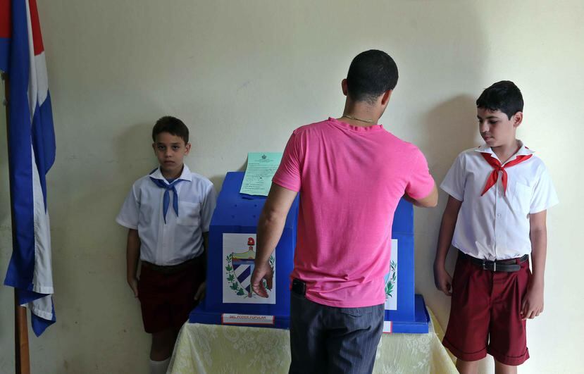 Un hombre vota ante la mirada de dos niños en Cuba. (EFE)