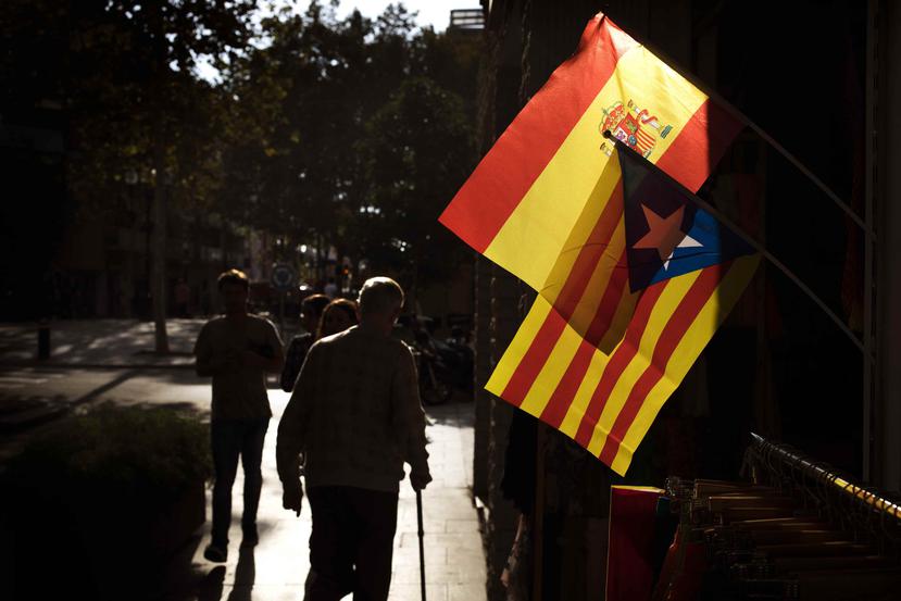 Gente caminando junto a una bandera española y una bandera independentista catalana. (AP)