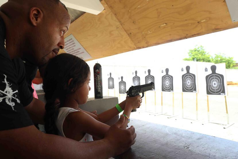 Un instructor enseña a una niña a utilizar un arma de fuego en las instalaciones de Lone Star Armory, en Cataño.
