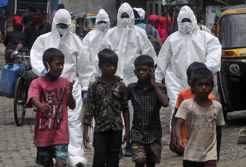 En esta fotografía de archivo del viernes 10 de julio de 2020, personal médico con ropa de protección llegan para examinar a personas que pudieran tener tener síntomas de COVID-19 en un barrio pobre en Mumbai, India.