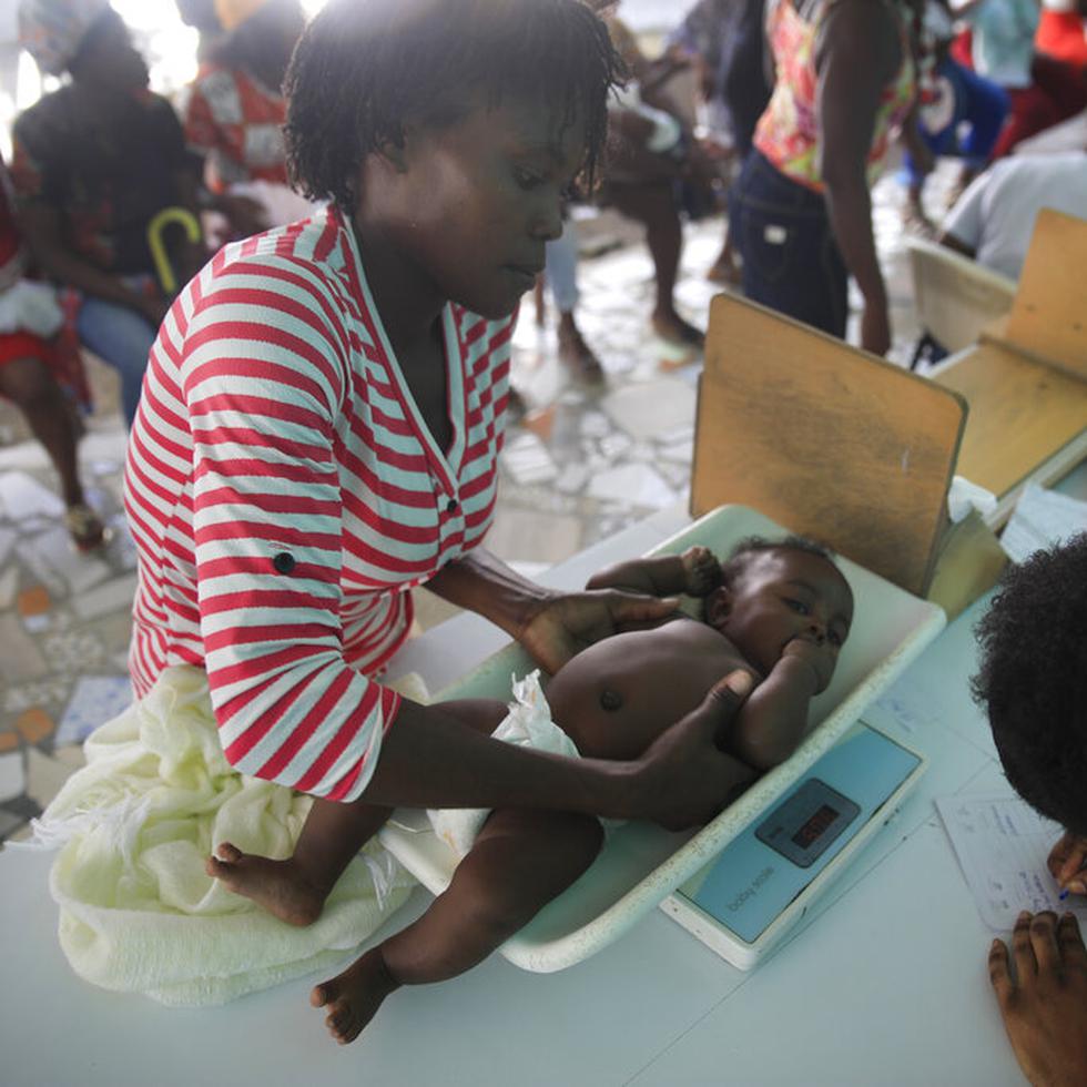 Una trabajadora de salud pesa a un niño en el Centro Hospitalario Fontaine, donde el bebé recibió varias vacunas, el lunes 23 de enero de 2023, en el barrio de Cité Soleil de Puerto Príncipe, Haití. (AP Foto/Odelyn Joseph)