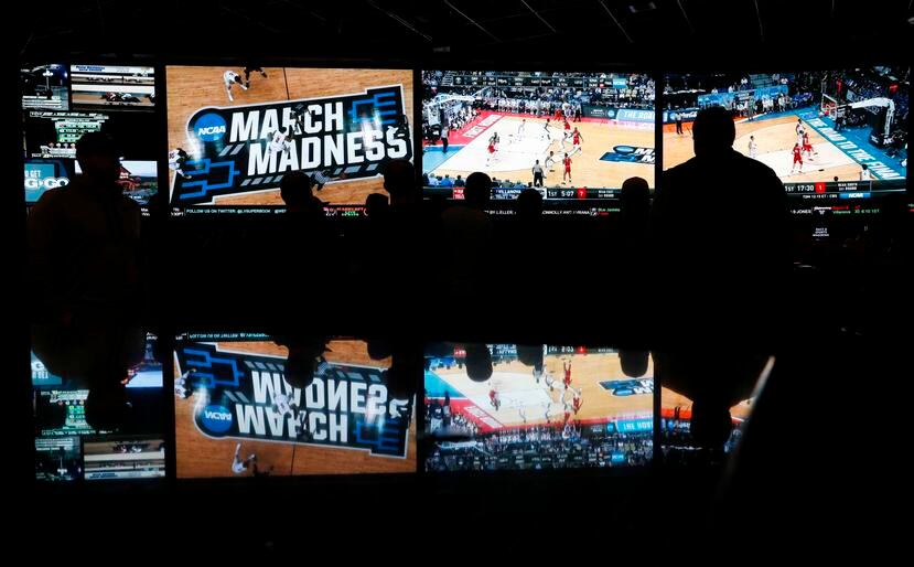 Varias personas miran la cobertura de la primera ronda del torneo de baloncesto colegial de la NCAA en Las Vegas.