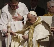 El papa Francisco sostiene un cirio al presidir un oficio de vigilia pascual en la Basílica de San Pedro.