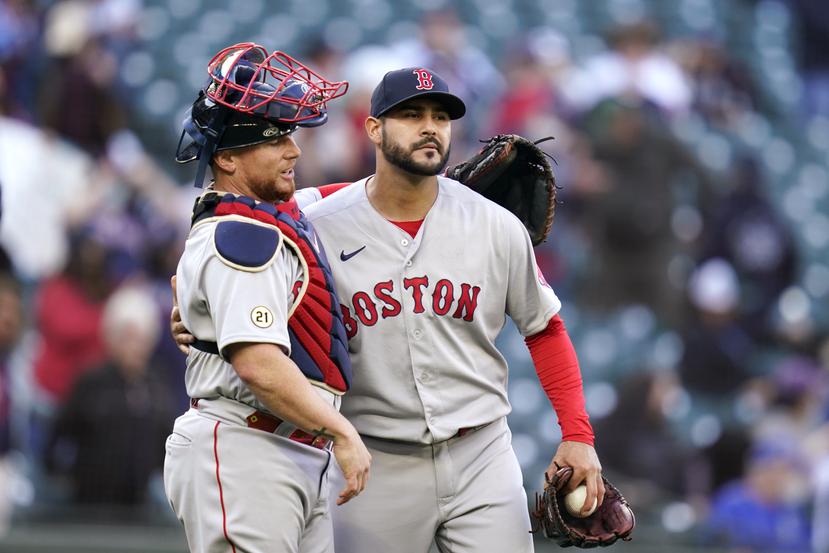 El receptor de los Red Sox de Boston, Christian Vázquez (izquierda), rodea con el brazo al lanzador Martin Pérez luego de que el equipo venciera a los Mariners de Seattle.