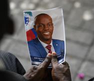 Una persona agarra la foto del presidente asesinado Jovenel Moïse.