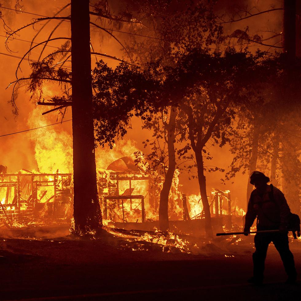 Un bombero camina cerca a un incendio forestal en California. Las autoridades investigan la causa de este fuego.
