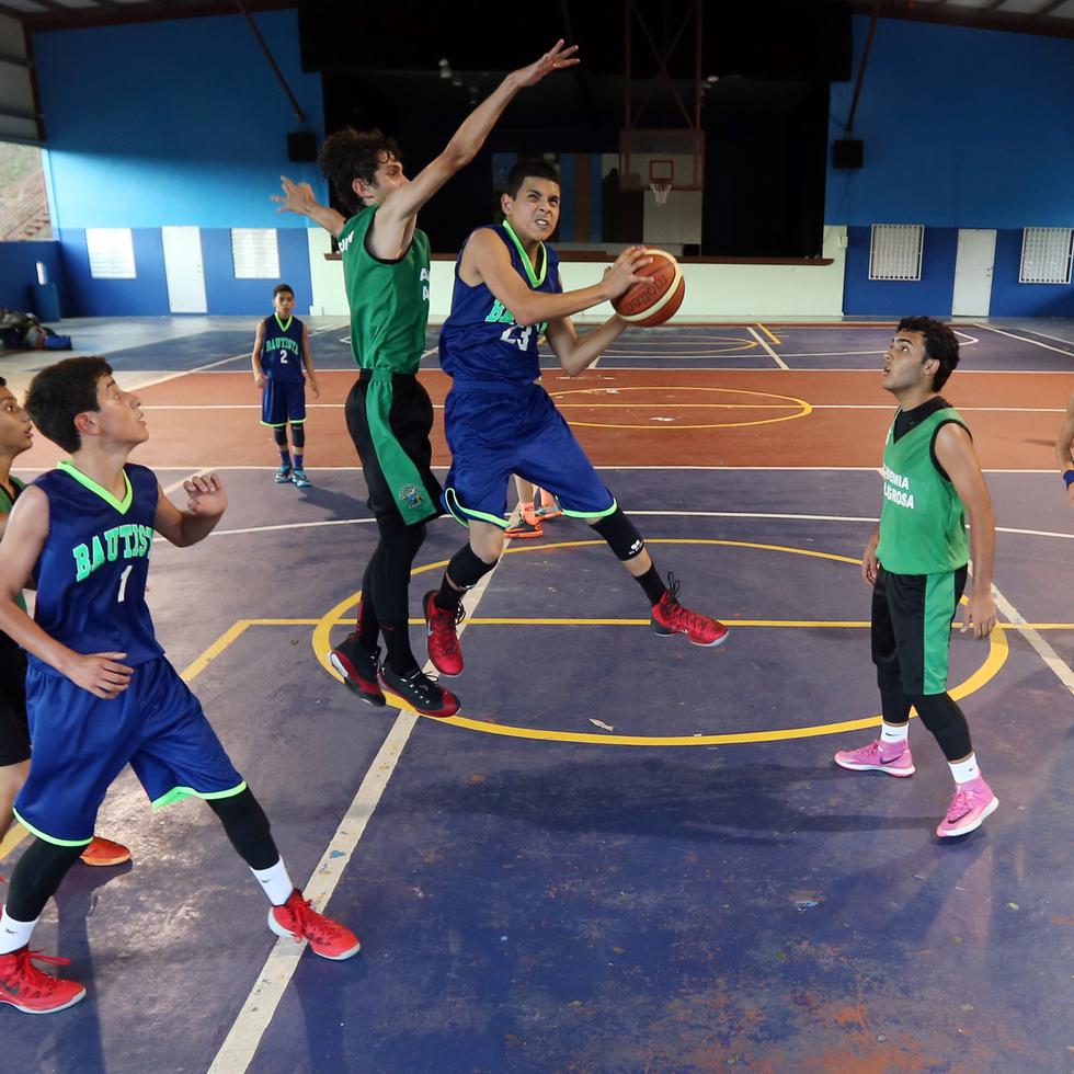 Un joven penetra hacia el canasto durante un torneo escolar. El baloncesto es uno de los 15 deportes que se incluyeron en el reglamento del DRD.