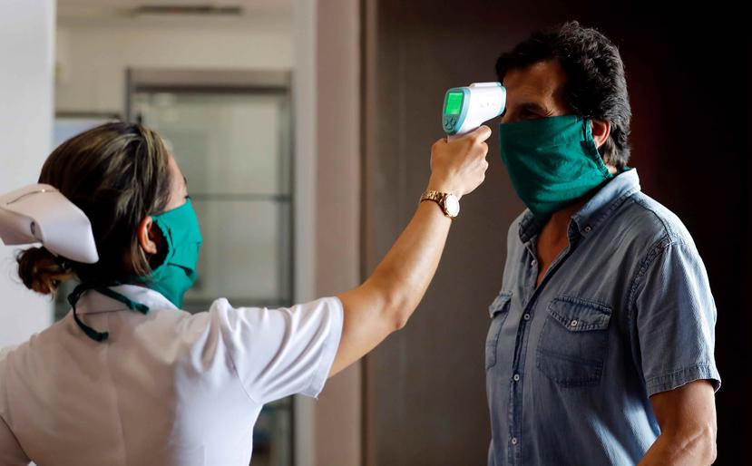 Una enfermera le toma la temperatura a un hombre en el Aeropuerto Internacional José Martí, en La Habana, Cuba. (EFE)
