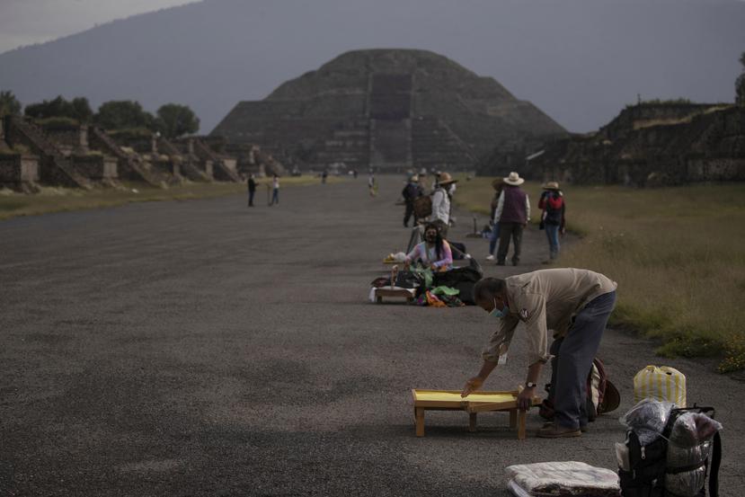 Vendedores de recuerdos y baratijas colocan sus artículos en la calzada que conduce a la Pirámide de la Luna en Teotihuacán, México, después de la reapertura de este sitio arqueológico tras un cierre de cinco meses a causa de la pandemia del coronavirus.