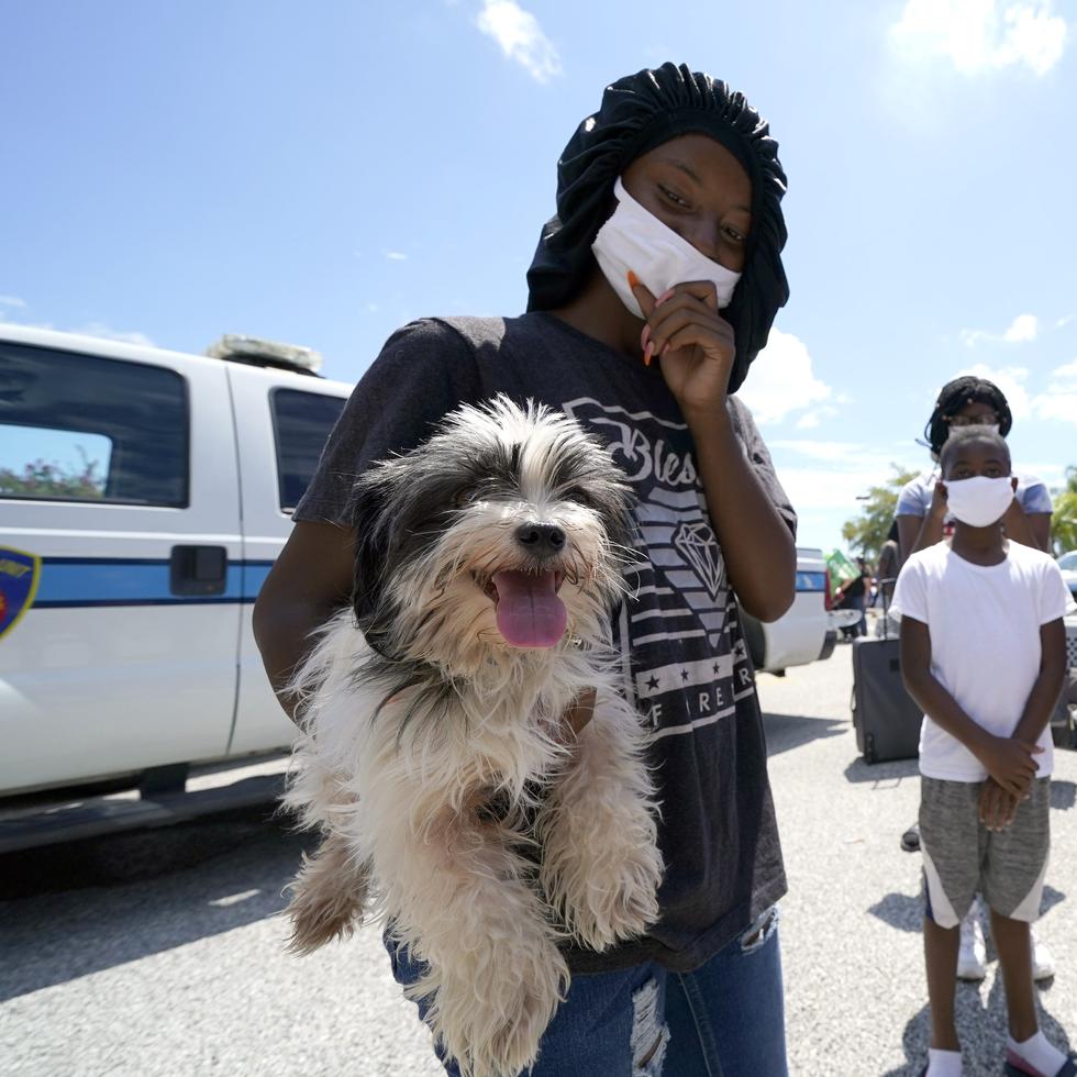 Tiara Walker holds her dog, Buece, as she waits with her family to board a bus to evacuate Tuesday, Aug. 25, 2020, in Galveston, Texas. The evacuees are being taken to Austin, Texas, as Hurricane Laura heads toward the Gulf Coast. (AP Photo/David J. Phillip)