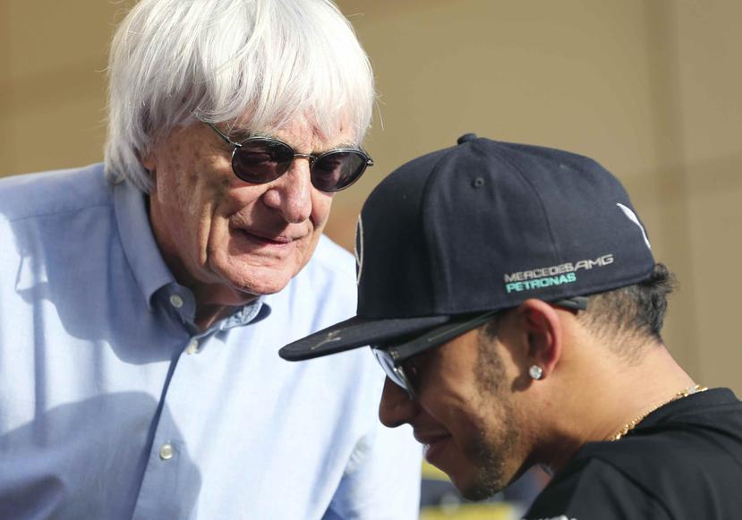 En esta foto de archivo del 16 de abril de 2015, Bernie Ecclestone, ahora expresidente de la Fórmula Uno, habla con el piloto británico Lewis Hamilton, antes del Gran Premio de Bahréin. (AP / Kamran Jebreili)