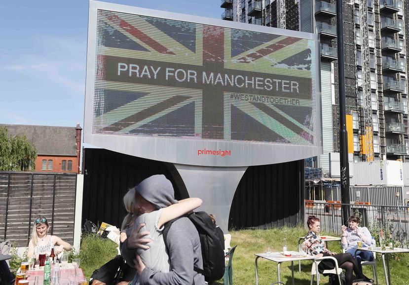 Foto de archivo, 23 de mayo de 2017, de una pareja abrazada bajo un cartel en Manchester, Inglaterra, al día siguiente de un ataque suicida en un concierto de Ariana Grande que dejó más de 20 muertos en la Manchester Arena. (AP Foto/Kirsty Wigglesworth, F