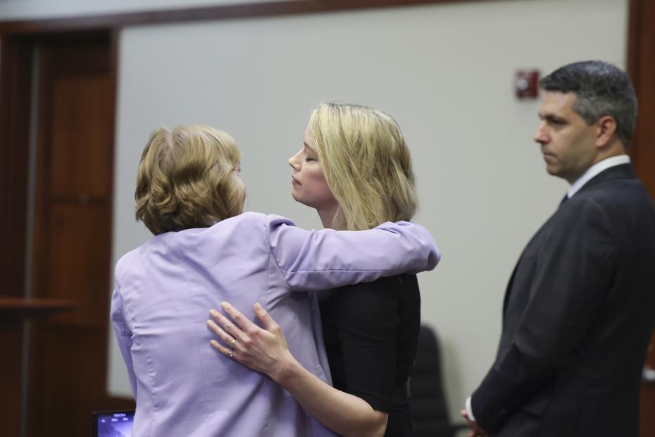 Actress Amber Heard hugs her attorney Elaine Bredehoft as Benjamin Rottenborn looks on after the verdict was read.