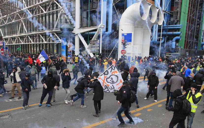 Manifestantes se alejan de los gases lacrimógenos arrojados por la policía durante una protesta contra la reforma al sistema de pensiones, en París. (AP/Michel Euler)