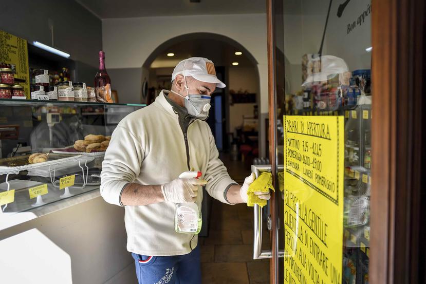 Un hombre limpia una puerta de una repostería en Italia.  (AP)