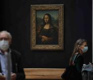 Dos personas caminan por la sala donde se encuentra la Mona Lisa de Leonardo da Vinci en el Museo del Louvre.