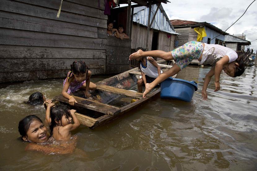 Niños juegan en un bote a las afueras de sus casas ubicadas en la comunidad de Belén, en Perú.