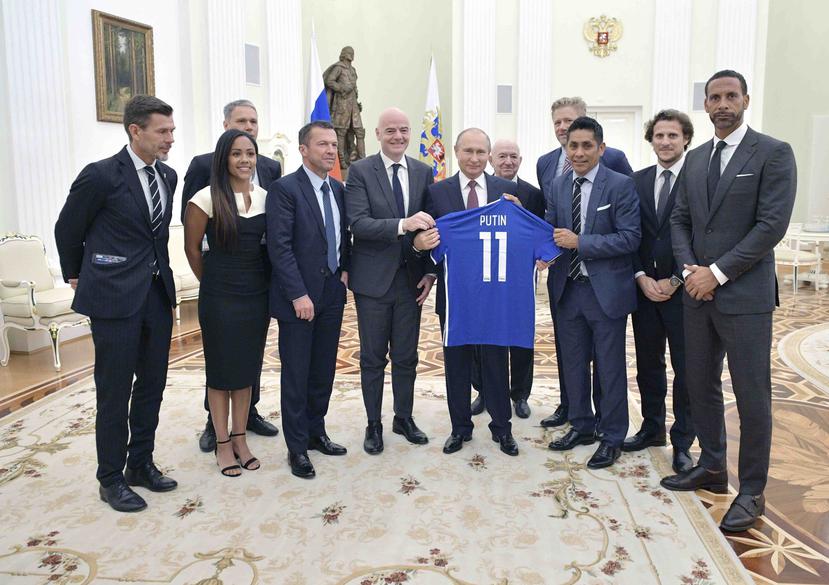 El presidente ruso Vladimir Putin sostiene una camiseta que le obsequiaron, junto al líder de la FIFA, Gianni Infantino, y varios exfutbolistas, al término de una reunión en el Kremlin. (AP)