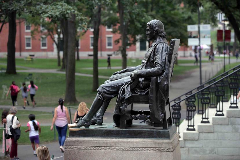 Estudiantes caminan frente a la estatua de John Harvard en la Universidad de Harvard en Cambridge, Massachusetts. (AP)