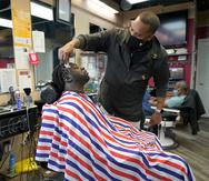 Mike Brown le corta el cabello a Vyron Cox Jr. mientras promueve la vacunación contra el COVID-19 en Hyattsville, Maryland.