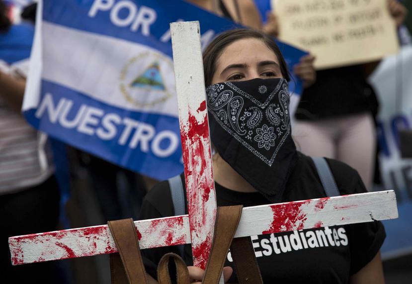 Una joven carga una cruz con una mochila en honor a los estudiantes que murieron en las pasadas manifestaciones contra el presidente Ortega. (EFE)