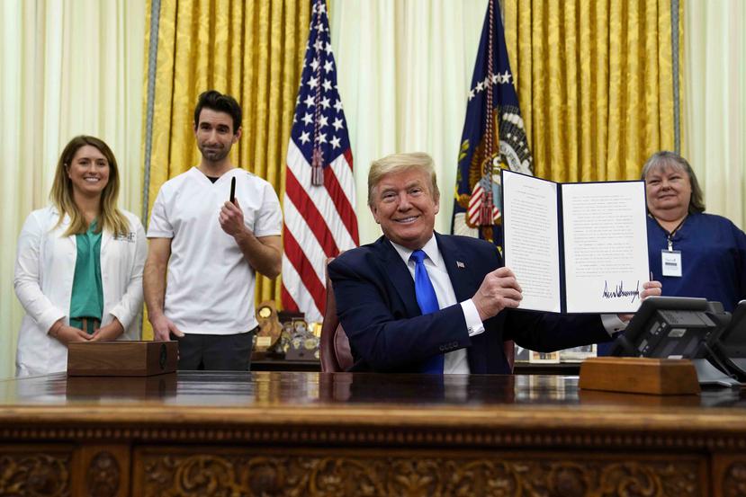 El presidente Donald Trump sostiene una proclamación firmada en honor del Día Mundial de la Enfermera durante un evento en la Oficina Oval de la Casa Blanca. (AP)