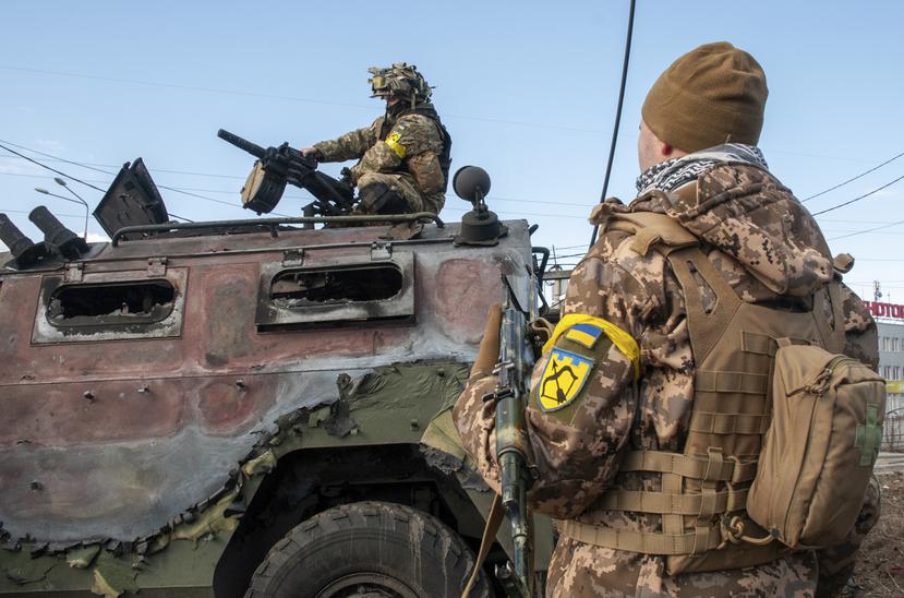 Soldados ucranianos inspeccionan un vehículo militar dañado.