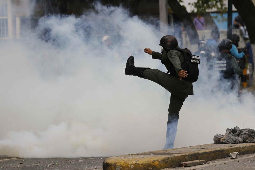 Un policía patea una lata de gas lacrimógeno durante una manifestación en contra del gobienrno de Nicolás Maduro. (AP)