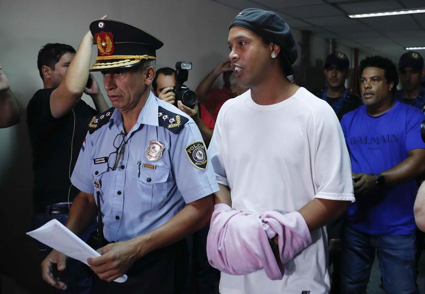 Ronaldinho (der.) es escoltado por un miembro de la policía de Paraguay. (AP / Jorge Saenz)
