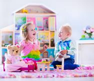 Menores jugando con una casa de muñecas.